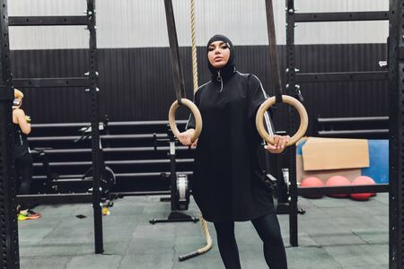 Muslim asian woman in hijab exercizing in a gym.
