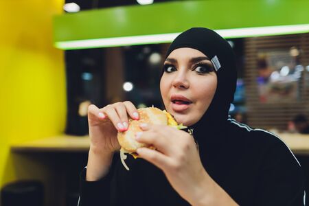 Arab girls at fast food restaurant eating burger.の写真素材