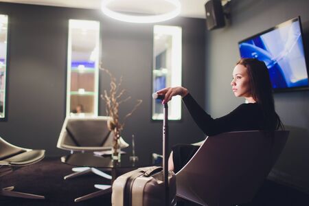 Businesswoman sitting at the airport lounge, waiting for the flight. Thoughtful woman sitting on sofa at airport waiting area.の写真素材