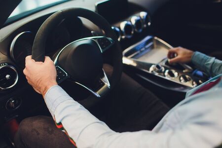Businessman driving luxury modern car in the city. Close up mans hand on the wheel of the car.