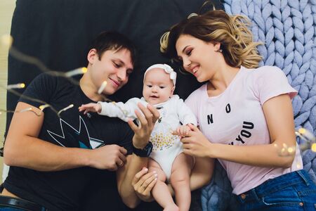 Parents cuddling baby in bed at home. Mom, dad and baby. Happy family concept.