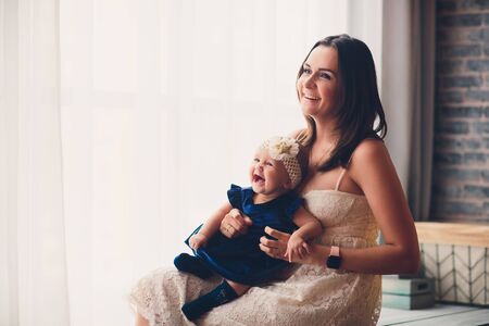 mom holds her lovely child tender standing in a room.