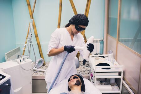 Woman in black mask on procedure carbon laser peeling.