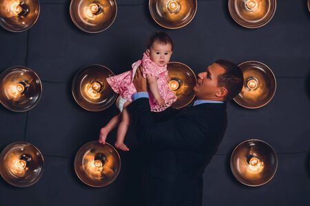 happy young father and his baby, against dark studio background.