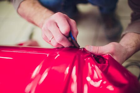 Car wrapping specialist putting vinyl foil or film on car. Selective focus.の写真素材