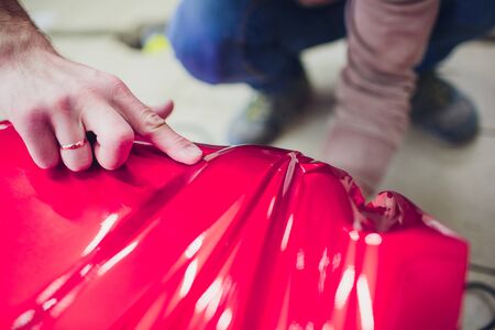 Car wrapping specialist putting vinyl foil or film on car. Selective focus.の写真素材