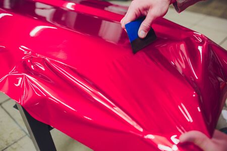 Car wrapping specialist putting vinyl foil or film on car. Selective focus.の写真素材
