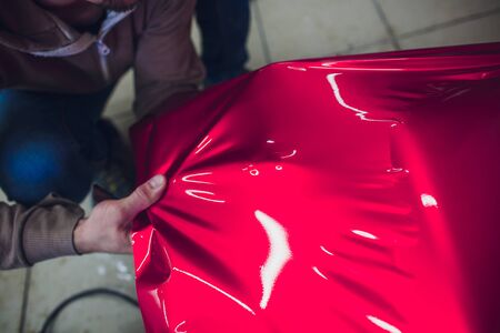 Car wrapping specialist putting vinyl foil or film on car. Selective focus.の写真素材