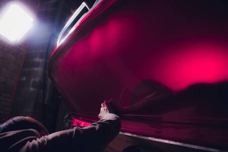 Car wrapping specialist putting vinyl foil or film car wrapping protective film yacht, boat, ship, car, mobile home. pink red film heating with hair dryer and trimming plastic soft hard squeegee.の写真素材