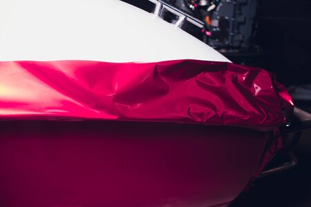 Car wrapping specialist putting vinyl foil or film on car wrapping protective film yacht, boat, ship, car, mobile home. pink red film.の写真素材