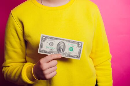 Hand holding 100 dollar bill. Isolated on a colored sweater.の写真素材