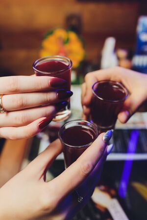 Friendship forever. Selective focus on three shots in blurry holding glasses