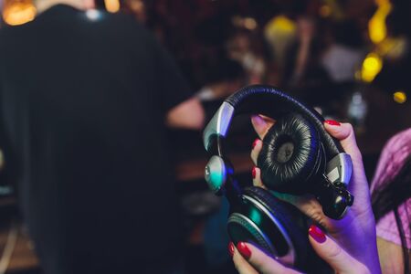 Female hands fold folding stereo headphones on a club backgroundの写真素材