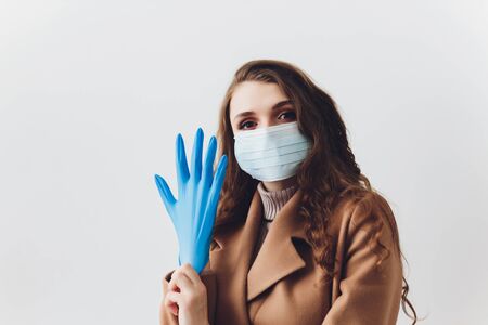 Scared young woman in medical mask standing over gray background.の写真素材
