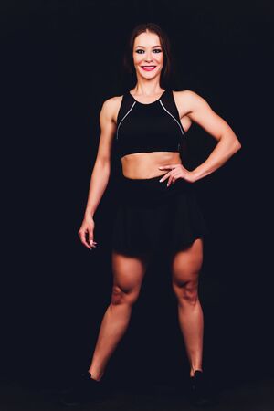 brunette female fitness model with perfect body posing on black background.の写真素材