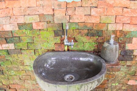 Black stone wash basin and vintage green mirrors. Retro orange brick background. Nature Bathroom decorated designの写真素材
