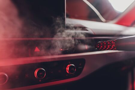 Handsome man cleaning car with hot steamの写真素材