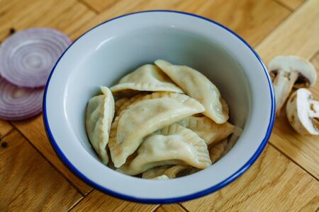 Boiled prepared homemade russian pelmeni, dumplings, ravioli with meat on grey plate with fresh parsley, pepper, wooden rustic background. Top viewの写真素材