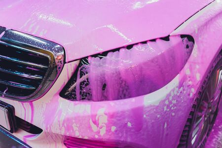 Close up cleaning car using high pressure water,High pressure jet washer in process of car washing pink color foamの写真素材