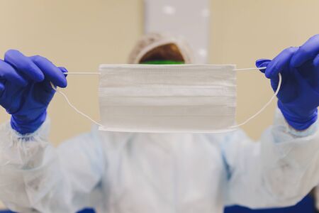 close up of doctors hand in medical gloves shows medical face mask for protection against infection.