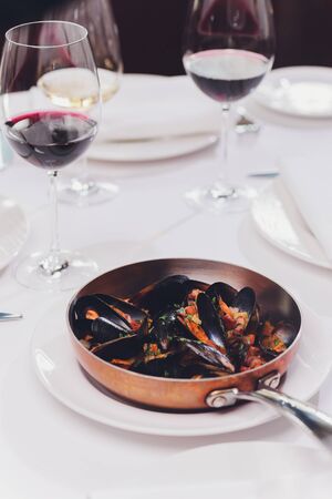 Boiled mussels in copper cooking dish on white background close up.
