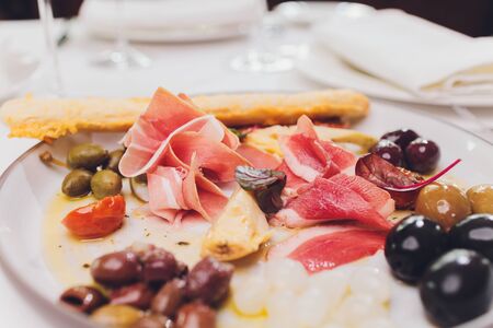 Meat appetizer selection. Salami, prosciutto, bread sticks, baguette, olives and sun-dried tomatoes,...