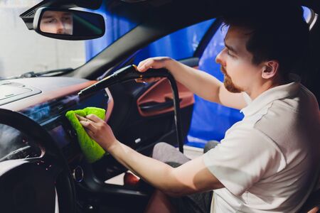 Handsome man cleaning car with hot steam.の写真素材