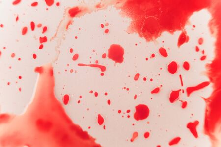 Fresh red blood splat on white porcelain with specks from the impact. Copy space area for horror themed concepts and ideas. macroの写真素材