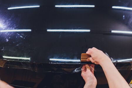 Transparent film, car paint protection, wrapping specialis. Car detailing. Selective focus.