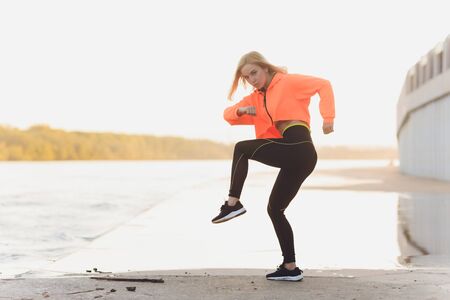 Healthy woman training on seaside promenade. Young attractive woman in sportswear does stretching...