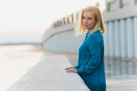 Woman in blue dress walks outdoors, summer day.の写真素材