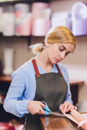 Female sales assistant working as florist and holding bouquet with customer in background....