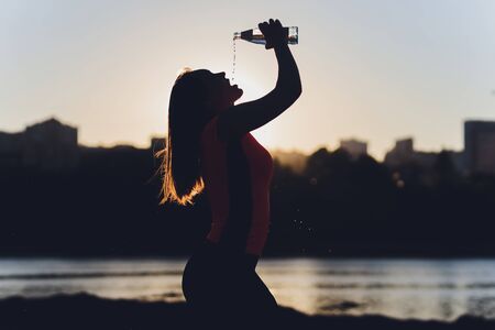 Slim young woman drinking water after training.の写真素材