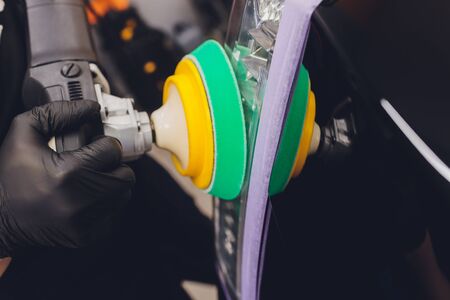 Car detailing - Hands with orbital polisher in auto repair shop. Selective focus.