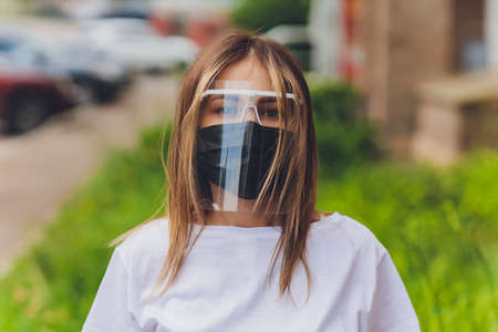 Portrait happy woman wile wearing a face shield for protection from cold and flu and viruses. Young woman with face mask in the street. Woman wearing face mask because of air pollution in the city.の写真素材