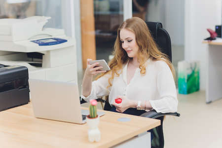 Portrait of a serious businesswoman using laptop in office. Beautiful hipster woman taking notes at...