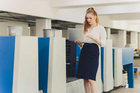 Young woman working in printing factory. Printing Press.