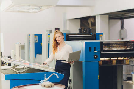 Young woman working in printing factory. Printing Press.の写真素材
