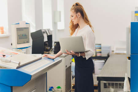 Young woman working in printing factory. Printing Press.の写真素材