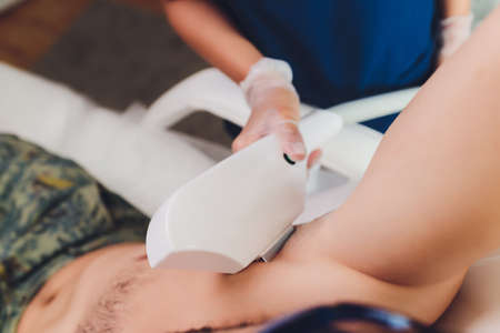 Young Man Receiving Laser Epilation Treatment From Beautician At Beauty Center.の写真素材