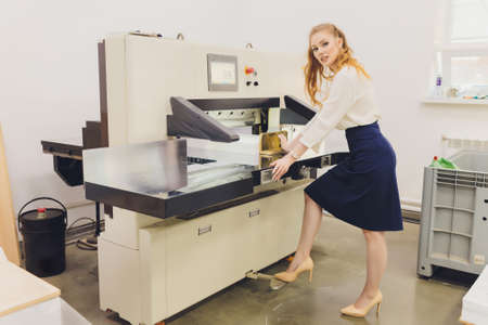 Young woman working in printing factory. Printing Press.