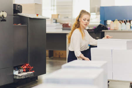 Young woman working in printing factory. Printing Press.