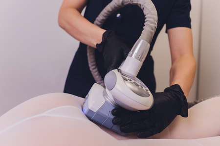 Parts of female body in special white suit having anti cellulite massage with spa apparatus.の写真素材