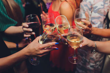 Close up shot of group of people clinking glasses with wine or champagne in front of bokeh background. older people hands.の写真素材