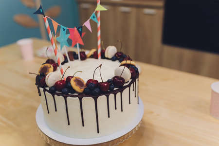 Beautiful tasty birthday cake and gifts on light background.