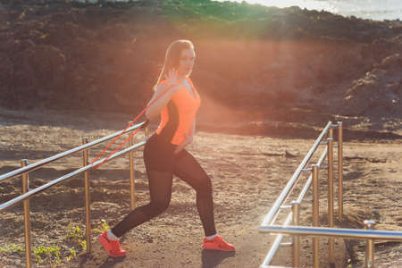 Young athletic wooman doing exercises with an elastic band. Fitness. Sport.