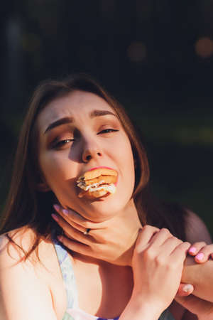 Smiling woman having a relaxing lunch break outdoors, she is sitting on the grass and eating.
