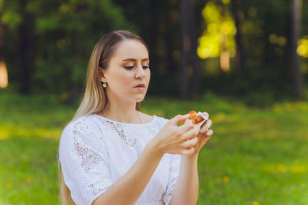 Smiling woman having a relaxing lunch break outdoors, she is sitting on the grass and eating.