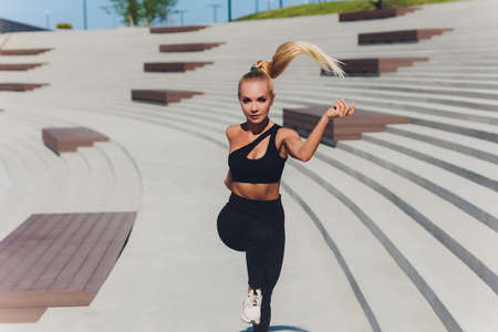 Running woman. Runner is jogging on sunrise. Female fitness model training outside in the city on a quay. Sport lifestyle.の写真素材