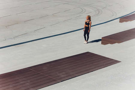 A young woman is preparing for outdoor sports on the modern promenade near her apartment complex.の写真素材